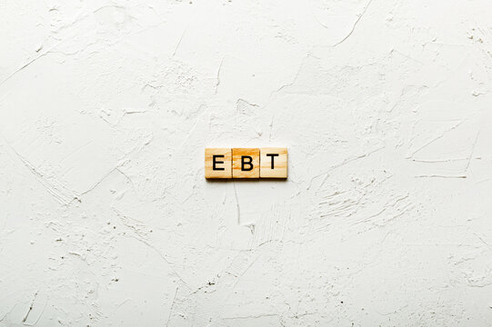 EBT word written on wood block. Abbreviation Earnings Before Taxes text on cement table for your desing, concept
