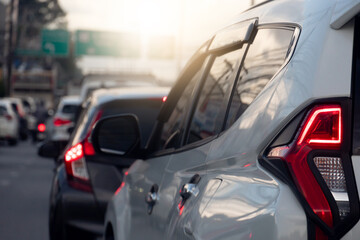 Rear side of white car on the aspahlt road. Transtport of car turn on brake light in the business time environment of moring time. Traffic congestion and queues of cars.