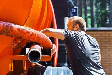 Sewer cleaning service - sewerage - repair workman on city street in working process to clean up...