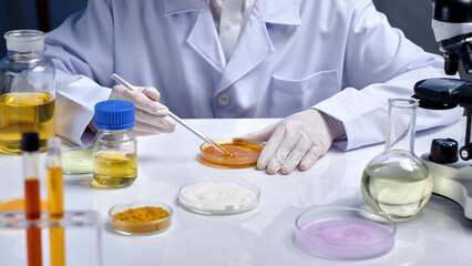 High angle shot photo at a white table top in laboratory, a researcher stirring yellow essence in...