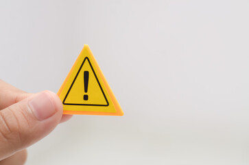 a hand holding a yellow warning sign emphasizes the importance of caution and awareness in various...