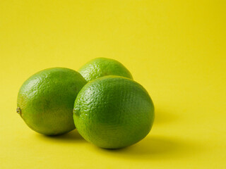 Close up, lime, tropical citrus fruit on yellow background and copy space.