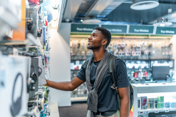 Young african man in a tech store looking at headphones