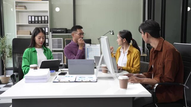 In a boardroom, an Asian team discusses startup financials and business terms. They present strategies on acquisitions, cash flow, and investor relations, innovative approaches for company growth.