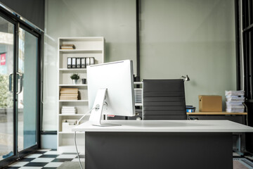 Fototapeta premium A modern office desk with a laptop, monitor, and plant. sleek, minimal design features open space, technology and productivity. room is empty, offering a clean and organized workspace.