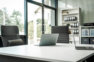 A modern office desk with a laptop, monitor, and plant. sleek, minimal design features open space, technology and productivity. room is empty, offering a clean and organized workspace.