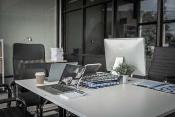 A modern office desk with a laptop, monitor, and plant. sleek, minimal design features open space, technology and productivity. room is empty, offering a clean and organized workspace.