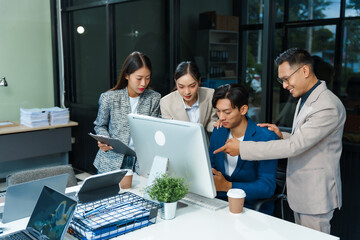 In an office, an Asian team meets at a desk, analyzing financial data on a monitor. They discuss business finance, operational guidelines, and strategies for success, data-driven decision-making.