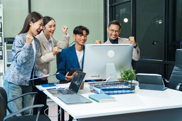 In an office, an Asian team meets at a desk, analyzing financial data on a monitor. They discuss...