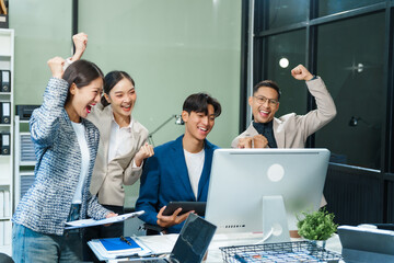 In an office, an Asian team meets at a desk, analyzing financial data on a monitor. They discuss...