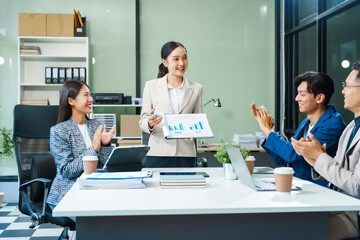 In a boardroom, an Asian team meets at a desk, presenting financial terms and strategies. Executives and employees collaborate, sharing ideas and work guidelines for success during an annual meeting.