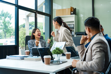 In a boardroom, an Asian team meets at a desk, presenting financial terms and strategies....