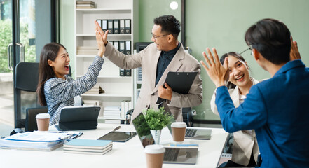 In a boardroom, an Asian team meets at a desk, presenting financial terms and strategies. Executives and employees collaborate, sharing ideas and work guidelines for success during an annual meeting.