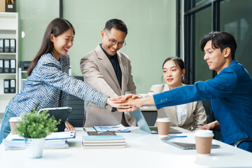In a boardroom, an Asian team meets at a desk, presenting financial terms and strategies....