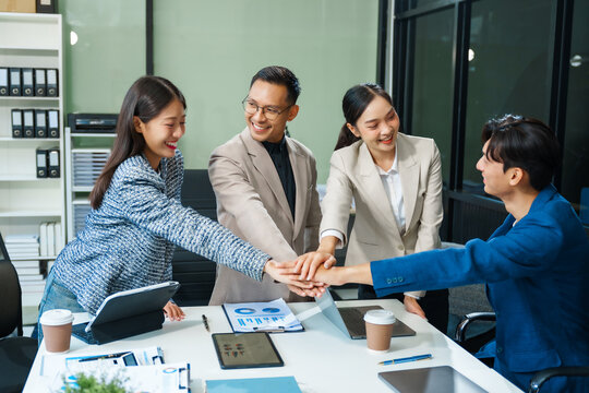 In a boardroom, an Asian team meets at a desk, presenting financial terms and strategies. Executives and employees collaborate, sharing ideas and work guidelines for success during an annual meeting.