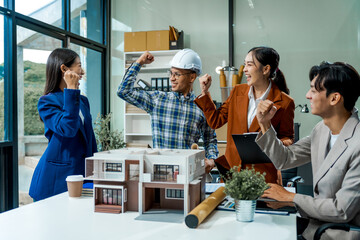 In an office room, architect-engineer team discusses modern house model at desk. They review...