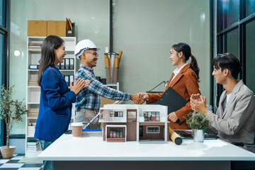 In an office room, architect-engineer team discusses modern house model at desk. They review...