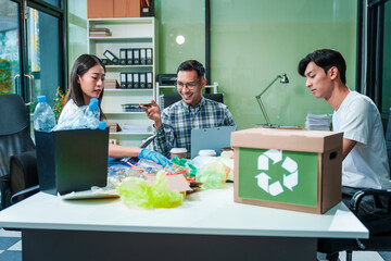 In an office, an Asian team discusses waste management strategies at a desk, separating plastic...