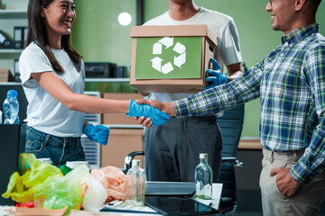 In an office, an Asian team discusses waste management strategies at a desk, separating plastic waste. They explore recycling systems and zero-waste goals to improve environmental sustainability.