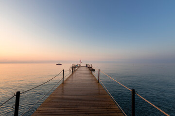 A pier with a boat in the water and a red flag on it