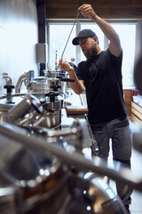 Brewery technologist examining equipment in brewing process, checking quality control standards in beer manufacturing. Concept of beer, brewery, manufacture, quality control