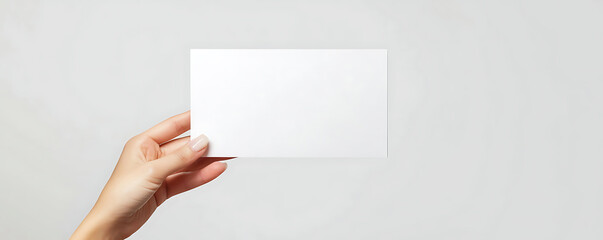 Obraz premium A close-up image of a hand holding a blank white flyer, perfect for design mockups or showcasing brochure designs