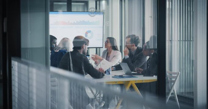 Diverse Team Working in a Conference Room. Managers Having Strategic Discussions During an Investing Presentation. Specialists Working in a Modern Glass Office, Using Computers and Paper Documents