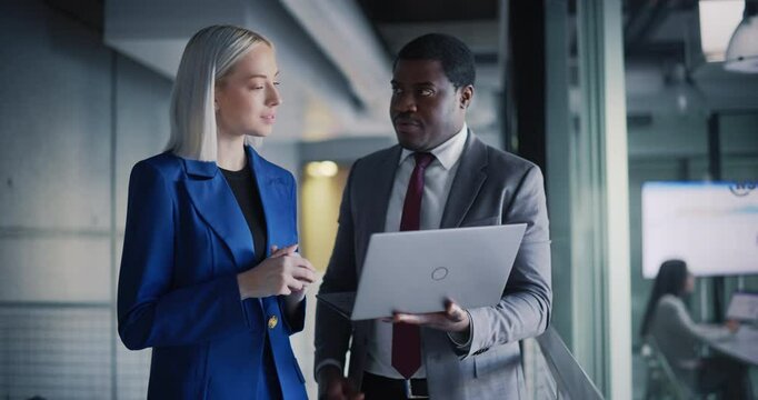 Black Male CEO and a Project Manager Standing in a Modern Office in Downtown Area. African Man and Caucasian Women Setting Up Business Meetings On a Laptop Computer, Checking Financial Reports