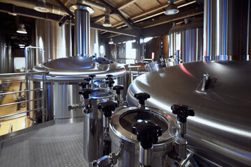 The shining surfaces of the brewery tanks and valves demonstrate the high standards of cleanliness and precision in the brewing process. Concept of beer, brewery, manufacture, quality control