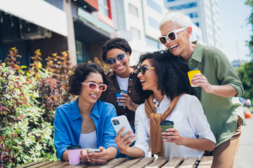 Portrait of company friends women use phone speak laugh free time street cafe table outdoors