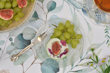 Dessert - cupcake with cream and fig decorated with green grapes on a glass plate. Top view decoration. 