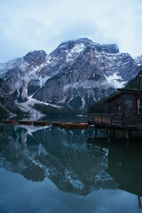 Fototapeta premium Turquoise water lake with rowing wood boats surrounded by pine trees and snowed mountains reflected in the Italian Alps, The Dolomites, Italy