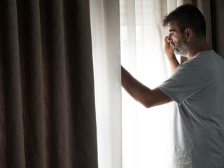 A sad and thoughtful man looks out of a window.Depression and anxiety are two of the major...