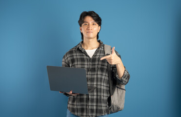 Portrait of Asian male student posing on blue background