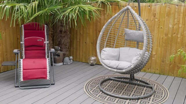Minimalistic UK summer garden showing swing chair decking and sun lounger.