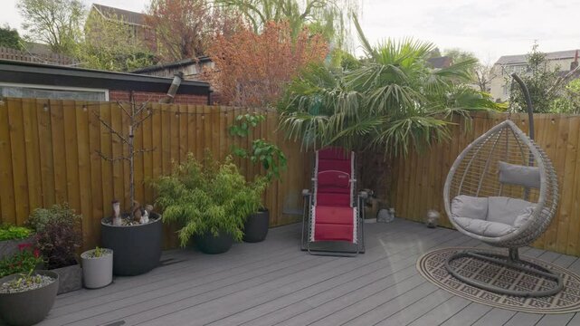 Minimalistic UK summer garden showing swing chair decking and sun lounger.
