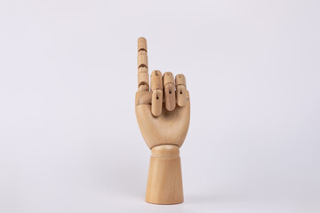 Wooden hand with raised index finger pointing upward with palm facing camera. Isolated on white...
