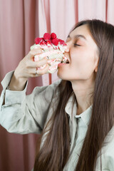 A woman is eating a cake with raspberries on it. She is smiling and she is enjoying her dessert