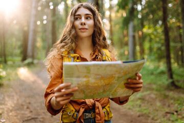A young woman explores a forest while reading a map in the sunlight, enjoying a beautiful day...