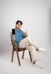 Portrait of young Asian business man sitting in chair, isolated on white background