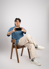 Portrait of young Asian business man sitting in chair, isolated on white background