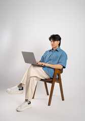 Portrait of young Asian business man sitting in chair, isolated on white background