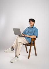 Portrait of young Asian business man sitting in chair, isolated on white background