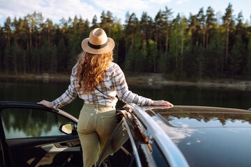 A joyful traveler embraces nature at sunset by the lakeside with an open car door, radiating...