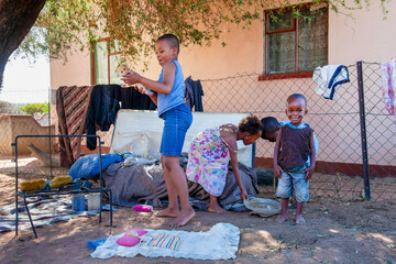 Four African children playing in the yard of the house in the village .Poverty, made up toys...