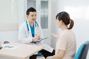 Obraz premium Asian female doctor listens to belly of pregnant mother during a prenatal exam in clinic. doctor provides caring advice, ensuring the health and happiness of the expecting mother and baby.