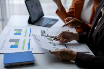 Two businesswomen analyzing financial charts and data on desk