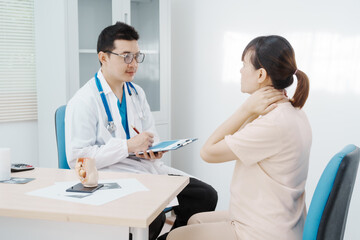 Asian female doctor listens to belly of pregnant mother during a prenatal exam in clinic. doctor provides caring advice, ensuring the health and happiness of the expecting mother and baby.