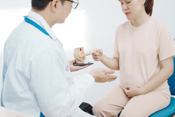 Obraz premium Asian female doctor listens to belly of pregnant mother during a prenatal exam in clinic. doctor provides caring advice, ensuring the health and happiness of the expecting mother and baby.