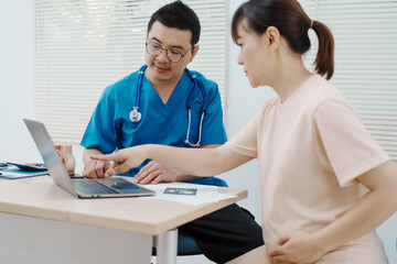 Fototapeta premium Asian female doctor listens to belly of pregnant mother during a prenatal exam in clinic. doctor provides caring advice, ensuring the health and happiness of the expecting mother and baby.